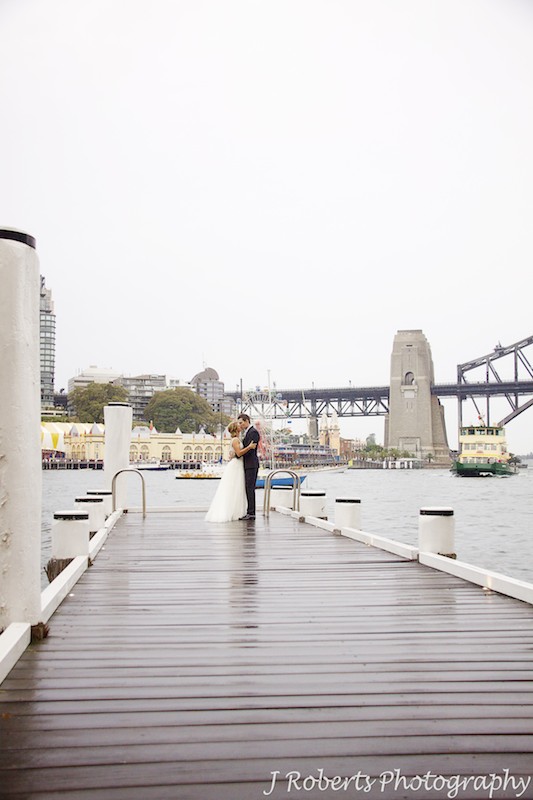 Couple kissing on a pier with Luna Park Sydney behind - wedding photography sydney